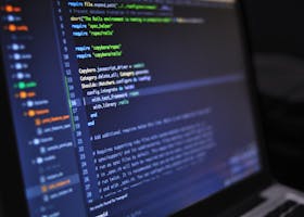 Close-up of a computer screen displaying programming code in a dark environment.